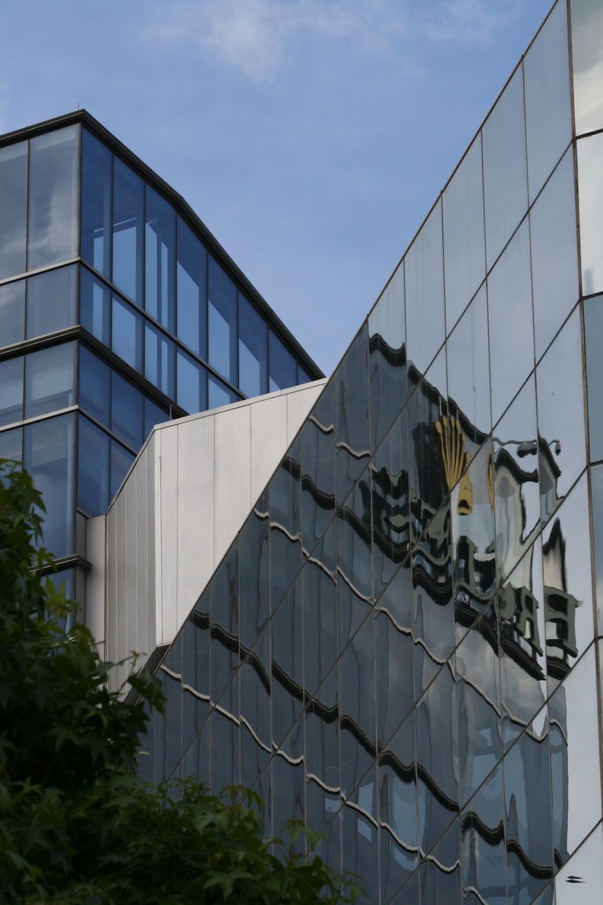 Reflective urban building facade beside an older commercial block