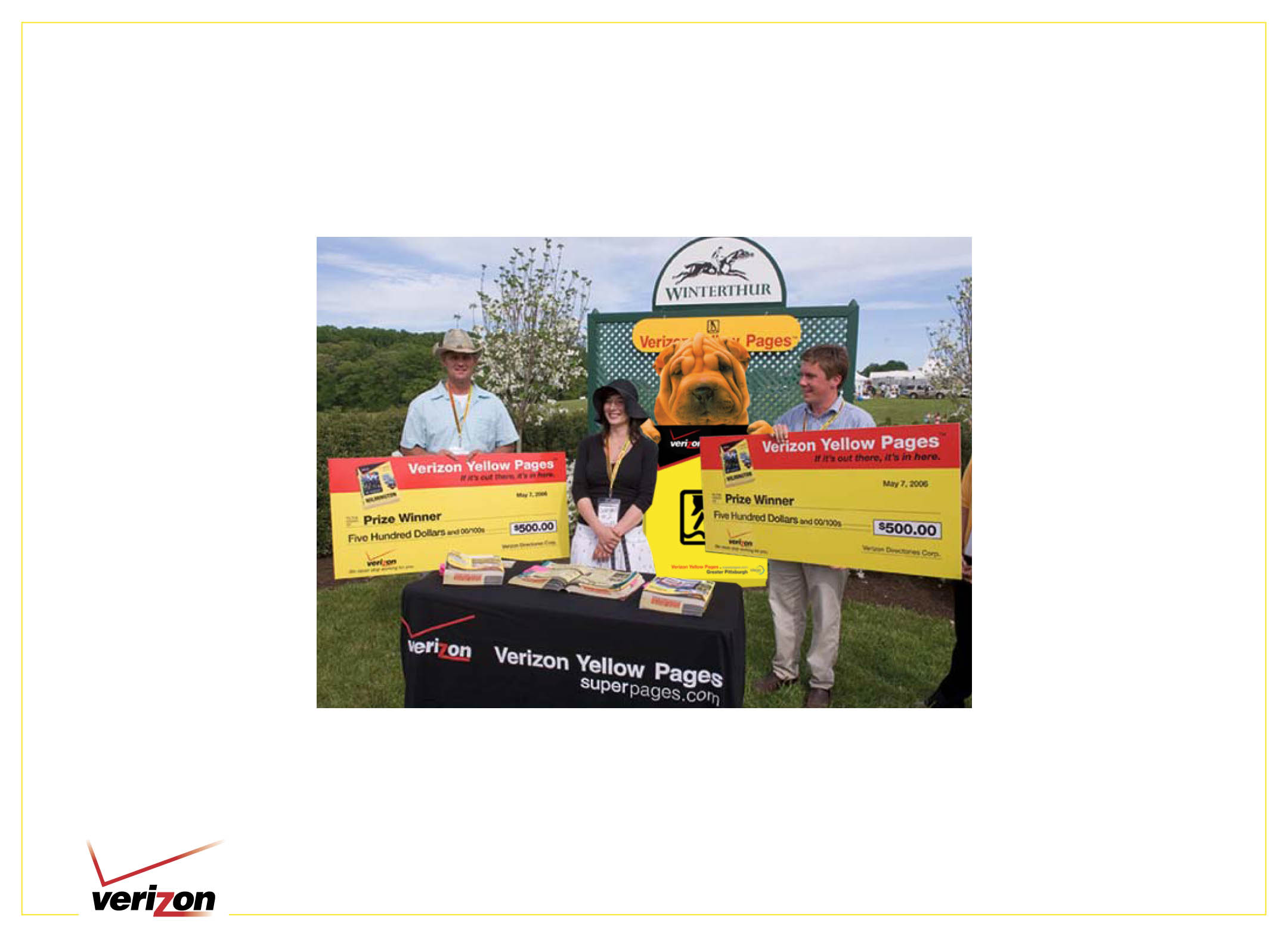 Verizon Yellow Pages event participants holding promotional checks beside Shar-Pei signage